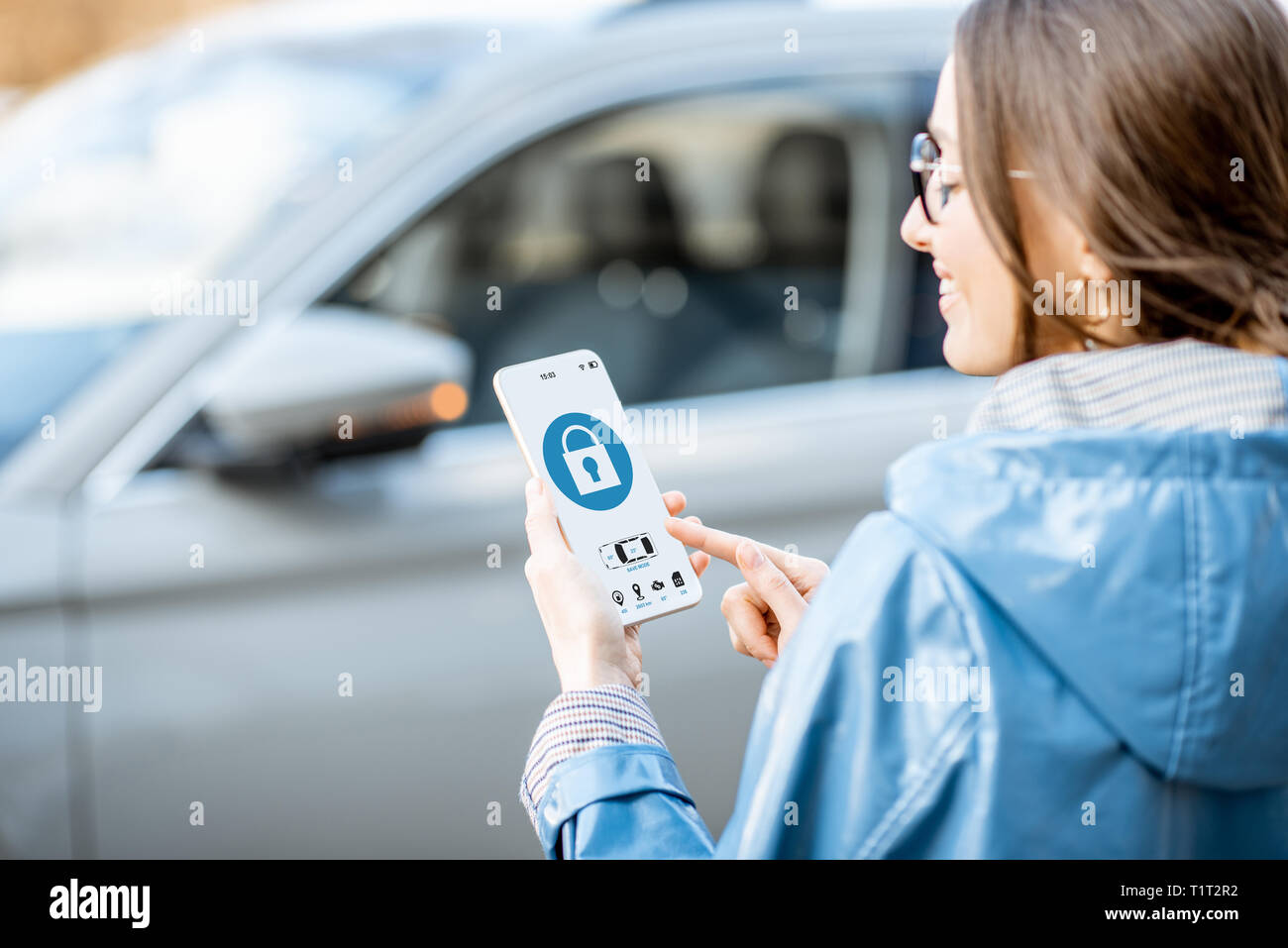 Donna auto di bloccaggio utilizzando l'applicazione mobile su un telefono intelligente. Concetto di controllo remoto e la protezione di auto attraverso internet Foto Stock