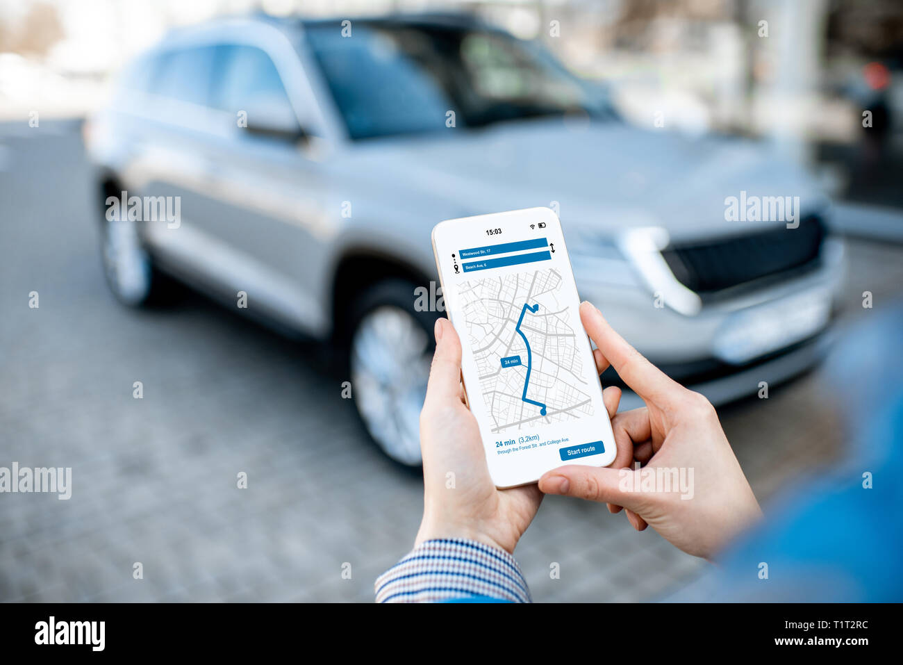 Donna che utilizza smart phone con navigazione app, vista da vicino con auto moderna sullo sfondo Foto Stock