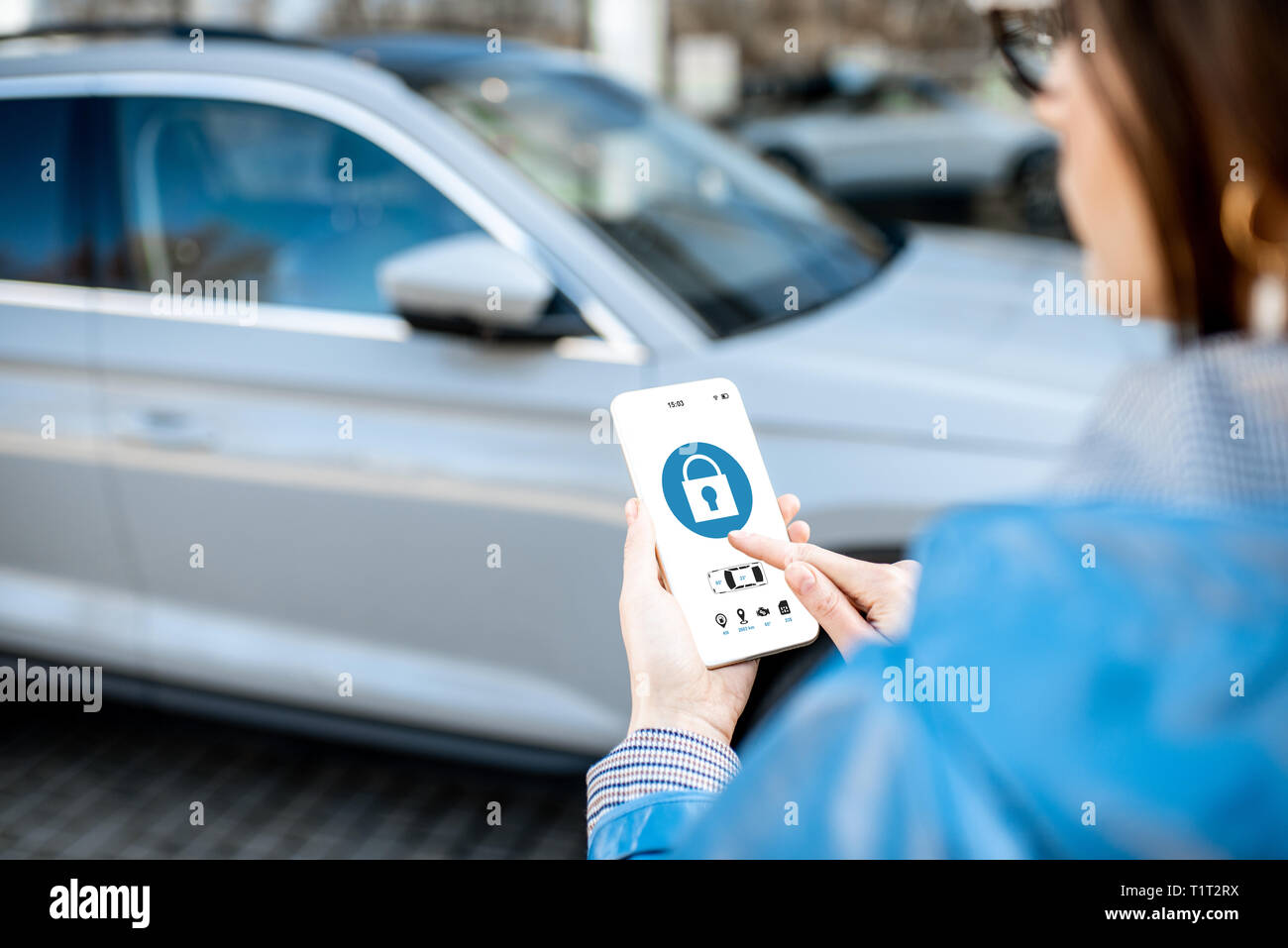 Donna auto di bloccaggio utilizzando l'applicazione mobile su un telefono intelligente. Concetto di controllo remoto e la protezione di auto attraverso internet Foto Stock