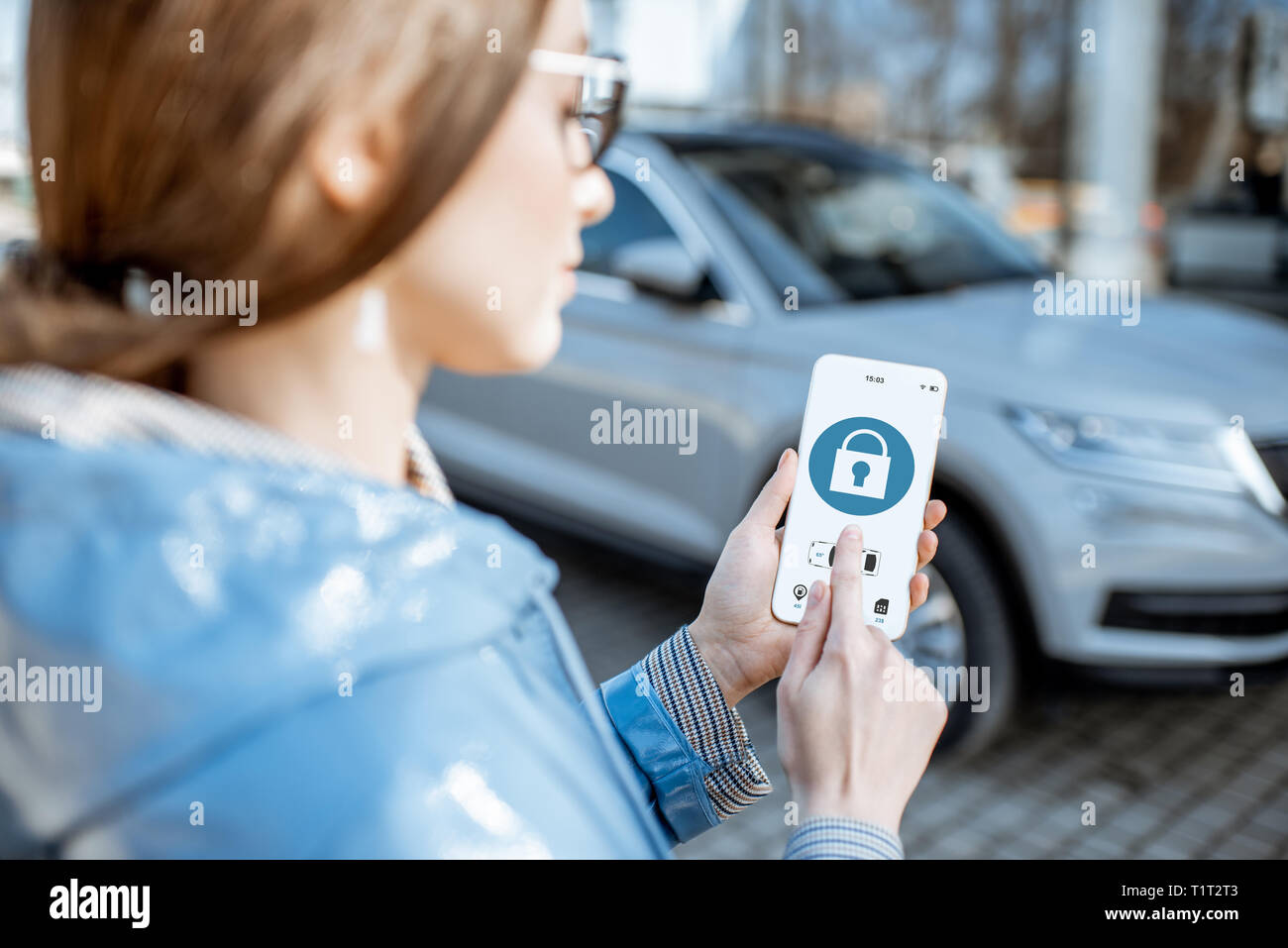 Donna auto di bloccaggio utilizzando l'applicazione mobile su un telefono intelligente. Concetto di controllo remoto e la protezione di auto attraverso internet Foto Stock