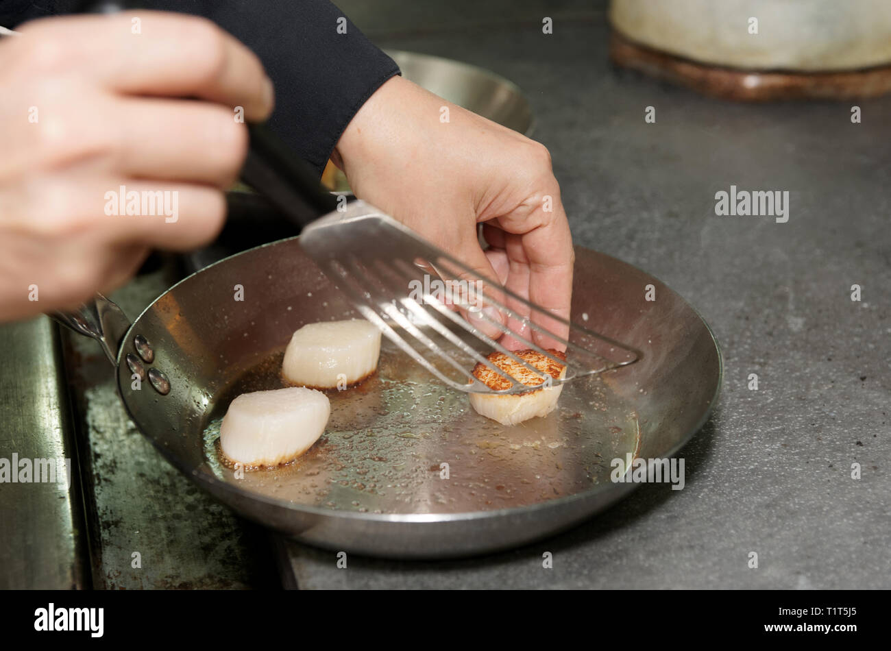 Lo chef è la frittura di capesante di mare sul pan Foto Stock
