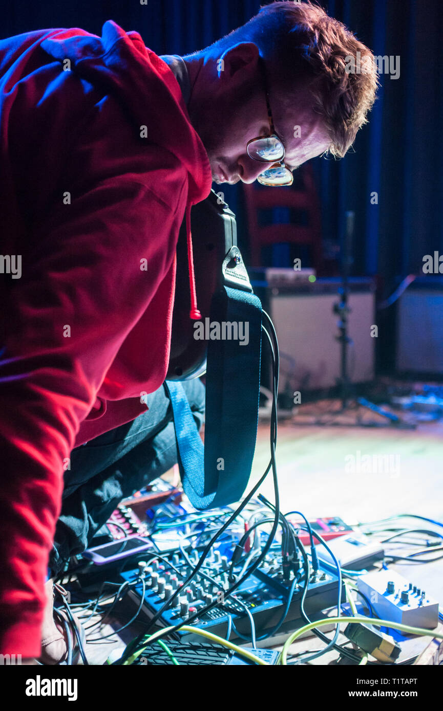 Un uomo suona musica sperimentale con una chitarra e una moltitudine di effetti processori, durante un assolo di prestazioni. Foto Stock