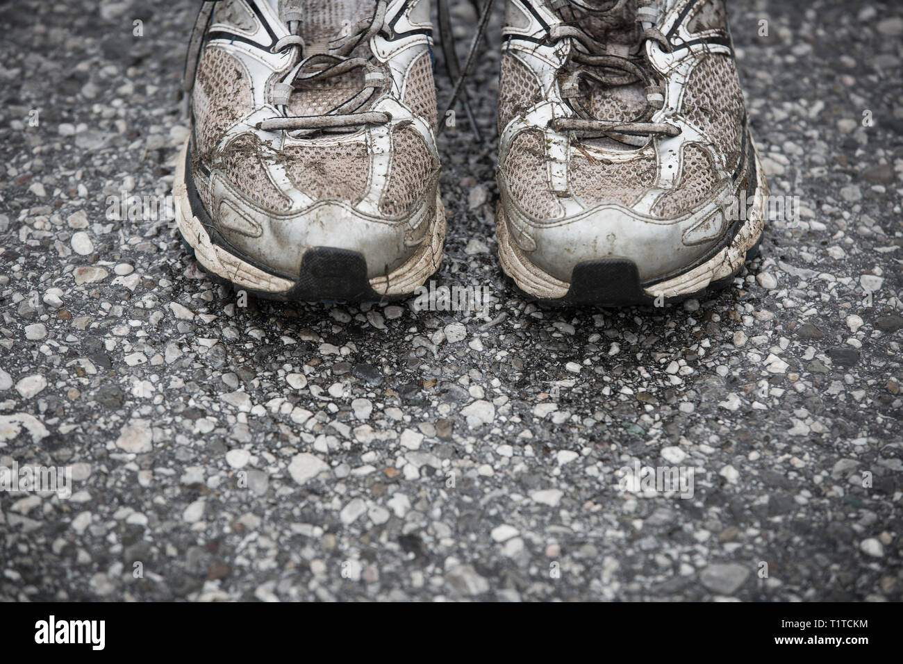 Usurato o sporco, puzzolente e vecchie scarpe da corsa su strada asfaltata. Corsa su strada, endurance, maratona postumi e uno stile di vita attivo concept. Foto Stock