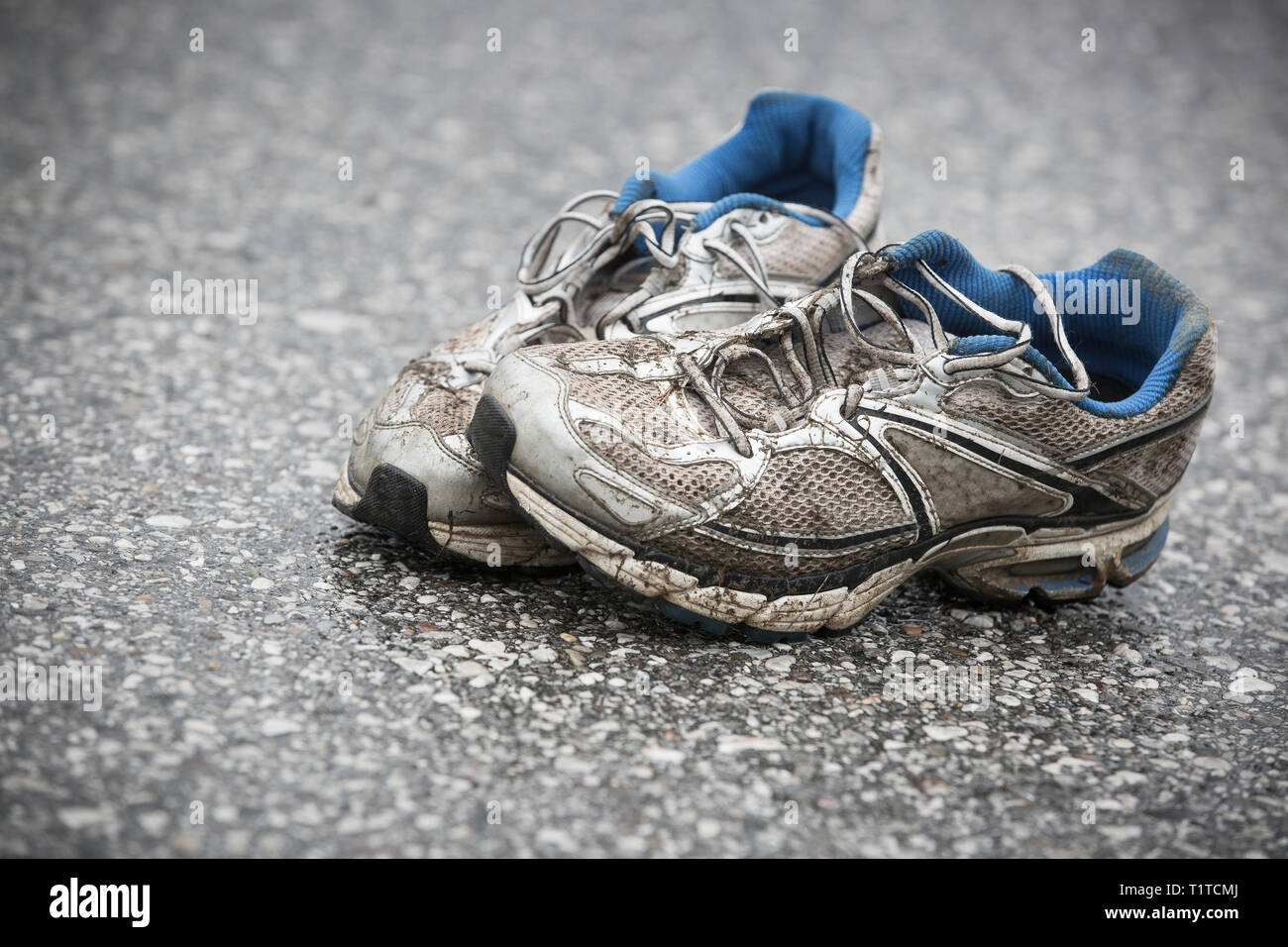 Usurato o sporco, puzzolente e vecchie scarpe da corsa su strada asfaltata. Corsa su strada, endurance, maratona postumi e uno stile di vita attivo concept. Foto Stock