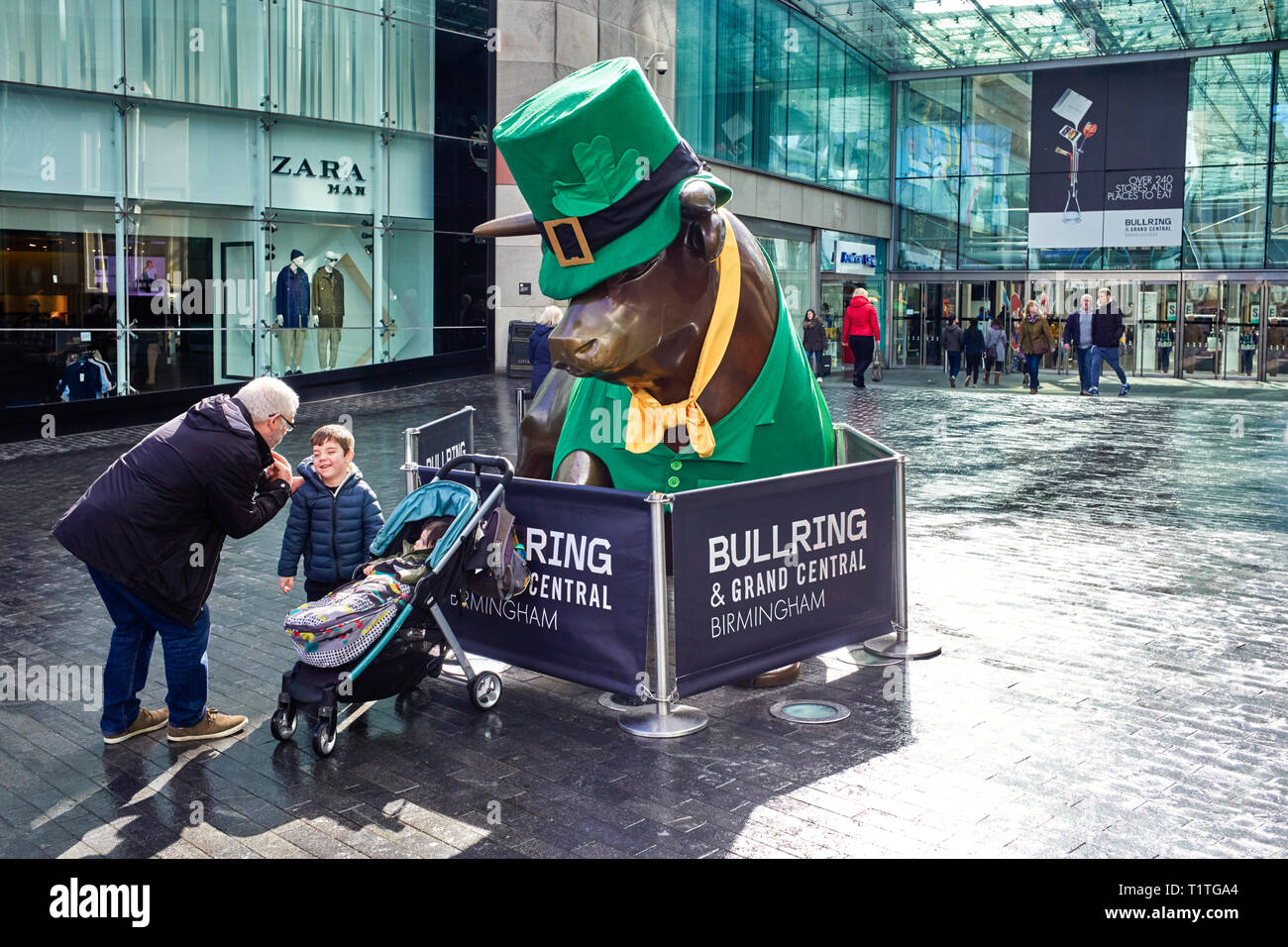 Un piccolo ragazzo appare riluttante ad avere la sua fotografia scattata nella parte anteriore del Bull Ring statua in Birmingham appositamente vestito di verde per St Patricks' Foto Stock