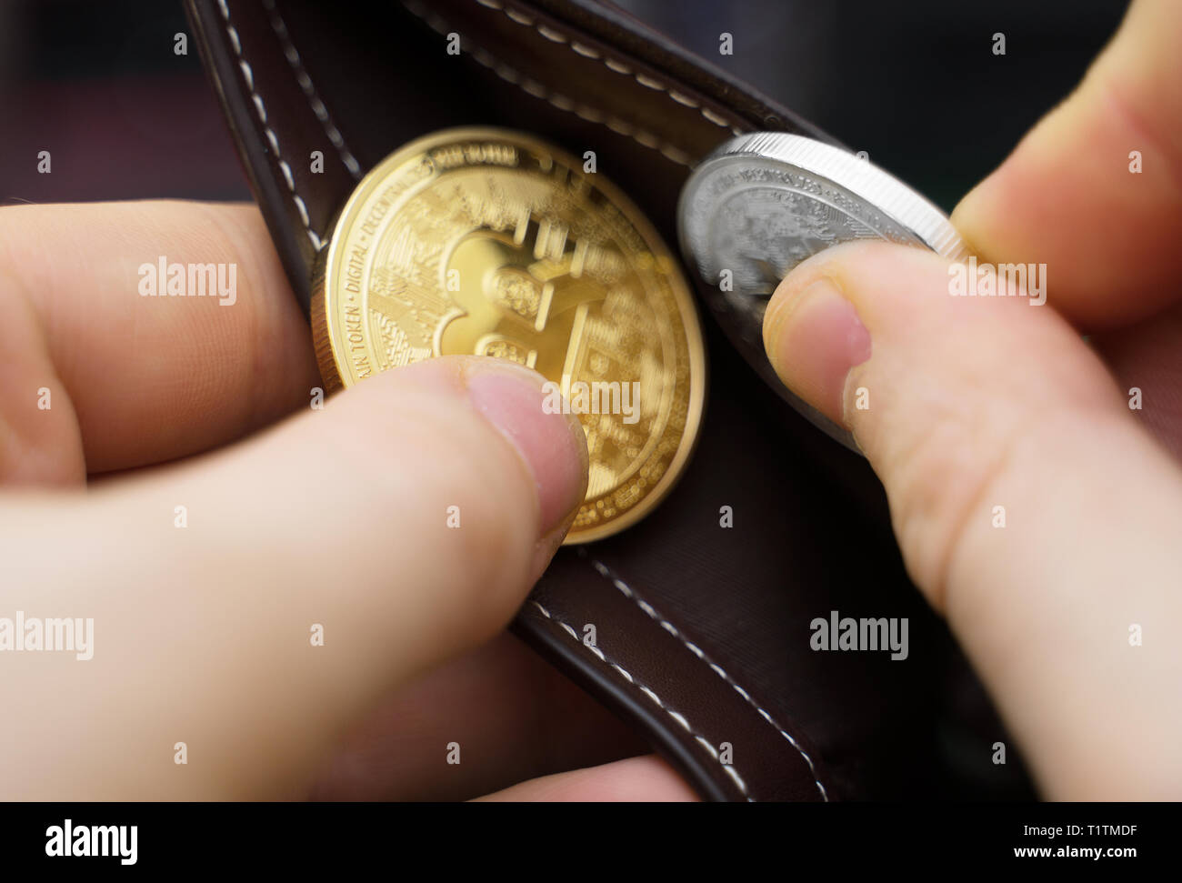 Uomo con la versione fisica di oro e di argento bitcoins. Foto Stock