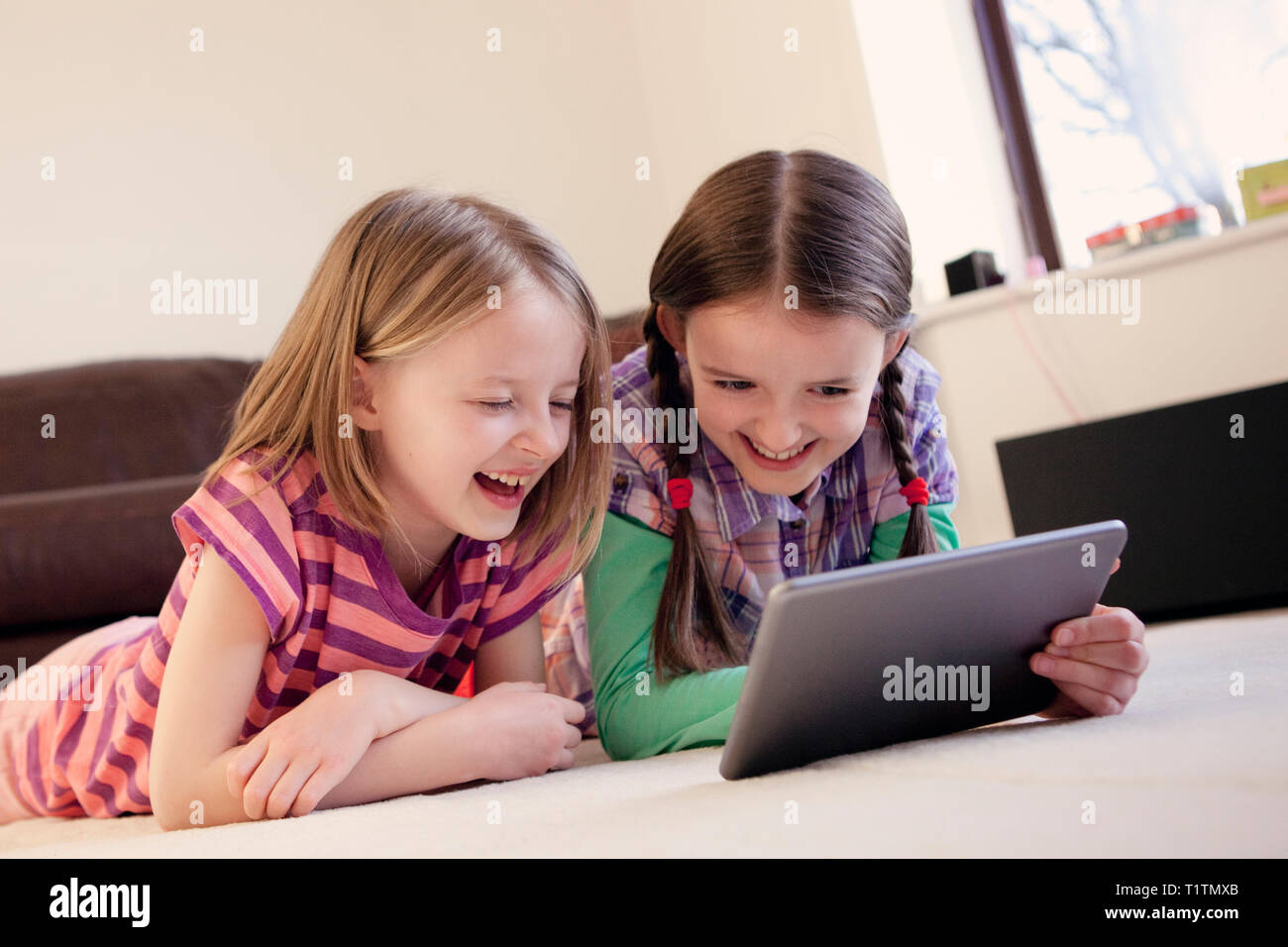 Due lieti, ridere i bambini utilizzando un dispositivo tablet pc insieme Foto Stock