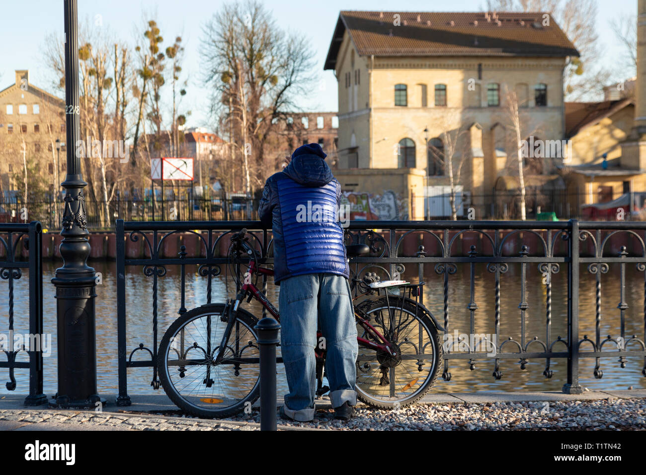 L'uomo con la bicicletta appoggiata su una ringhiera sul fiume Watlaw, Gadansk, Polonia Foto Stock