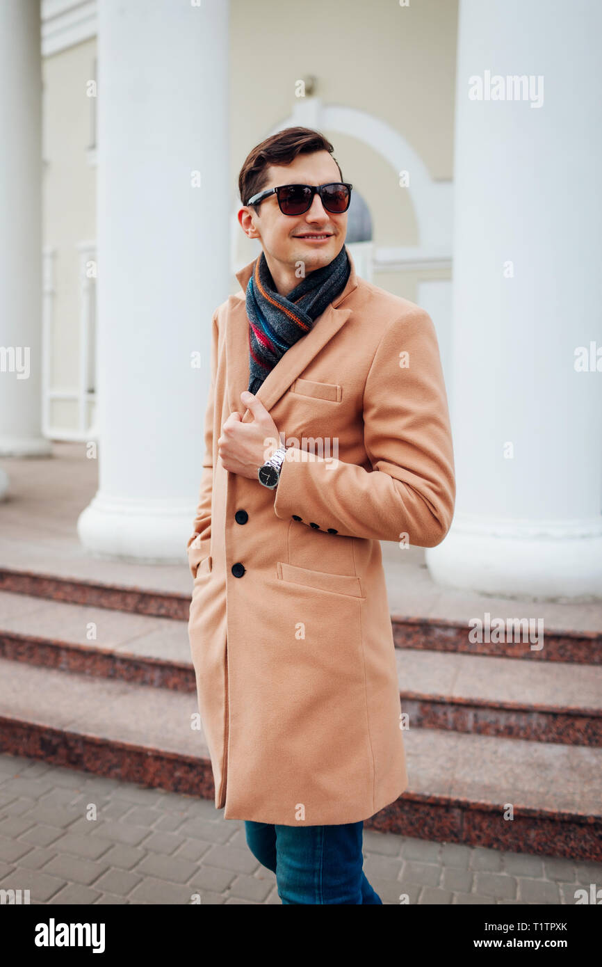 Felice giovane elegante uomo a camminare in città. Bel ragazzo indossa abiti classici e accessori. Street fashion. Foto Stock