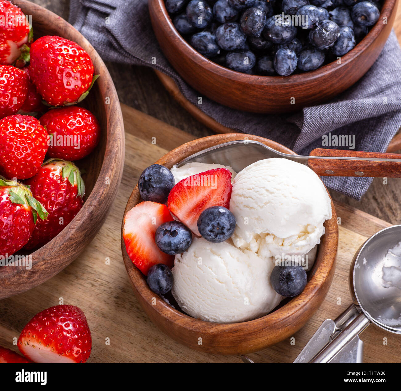 Vista aerea del gelato alla vaniglia con mirtilli freschi e le fragole in un recipiente di legno Foto Stock