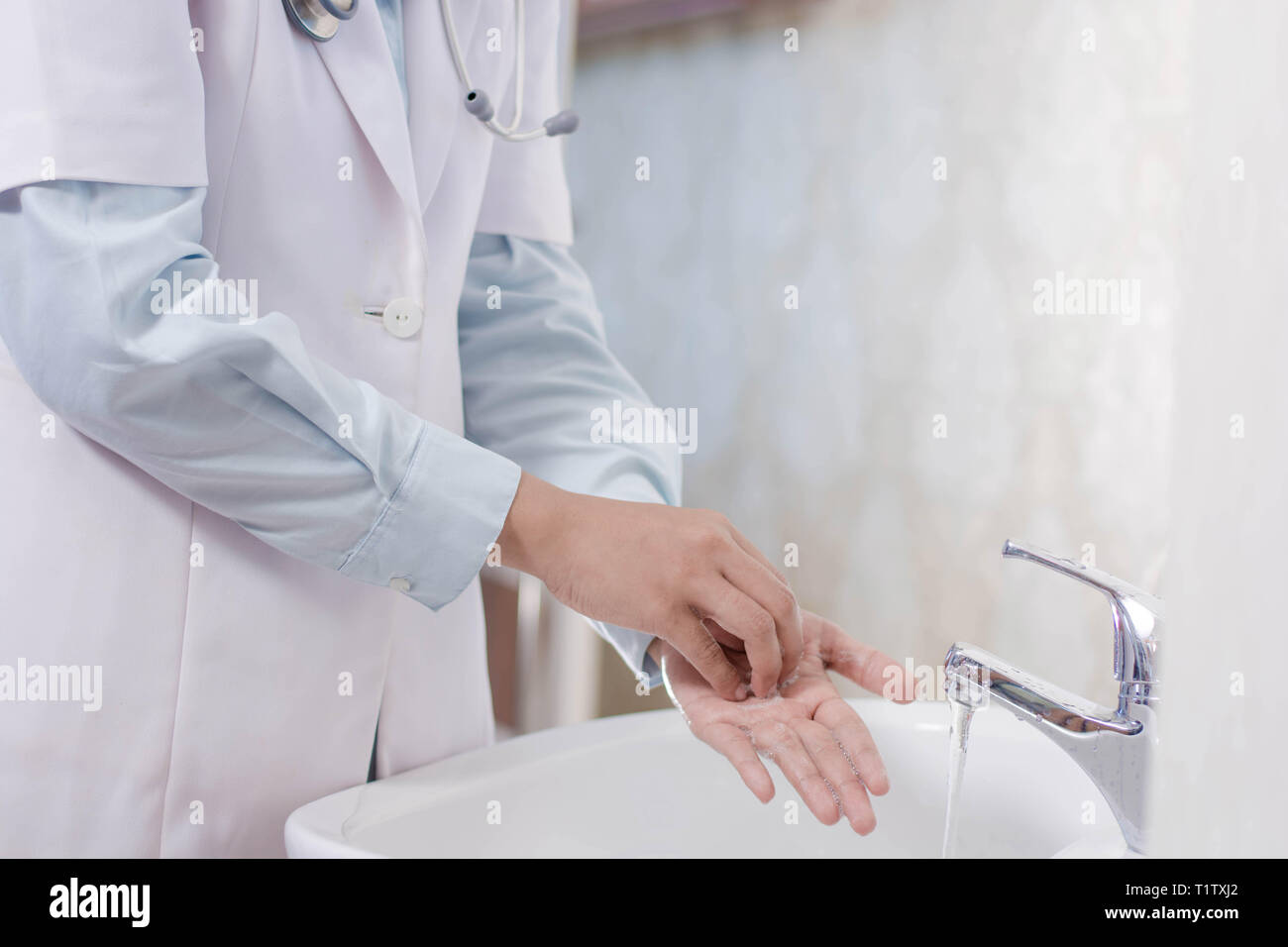 Medico donna lavaggio a mano nel lavandino con schiuma di sapone Foto Stock