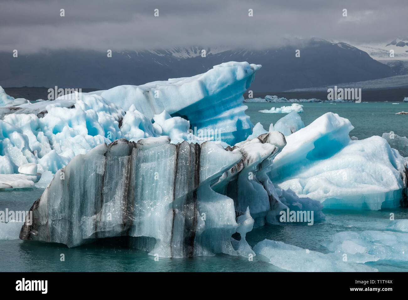 La fusione blu luminoso iceberg galleggianti in Jokulsarlon laguna glaciale, un popolare dastination di viaggio e una delle meraviglie naturali dell'Islanda. Bre Foto Stock