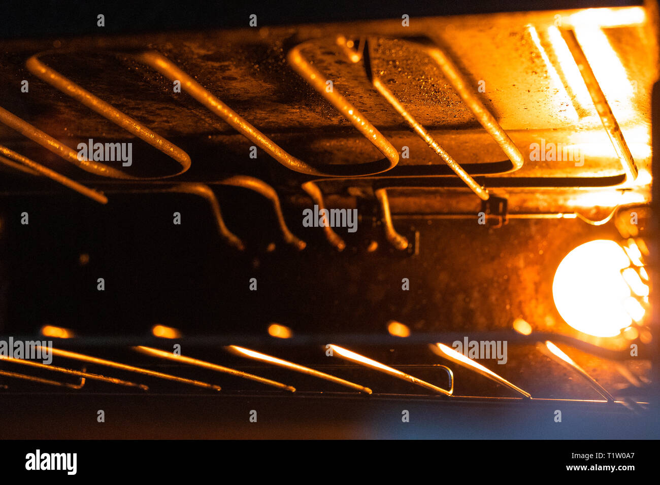 All'interno del forno/grill/fornelli con arancio brillante luce illuminante  sul reticolo metallico. Grill/forno apparecchio, fornello Foto stock - Alamy