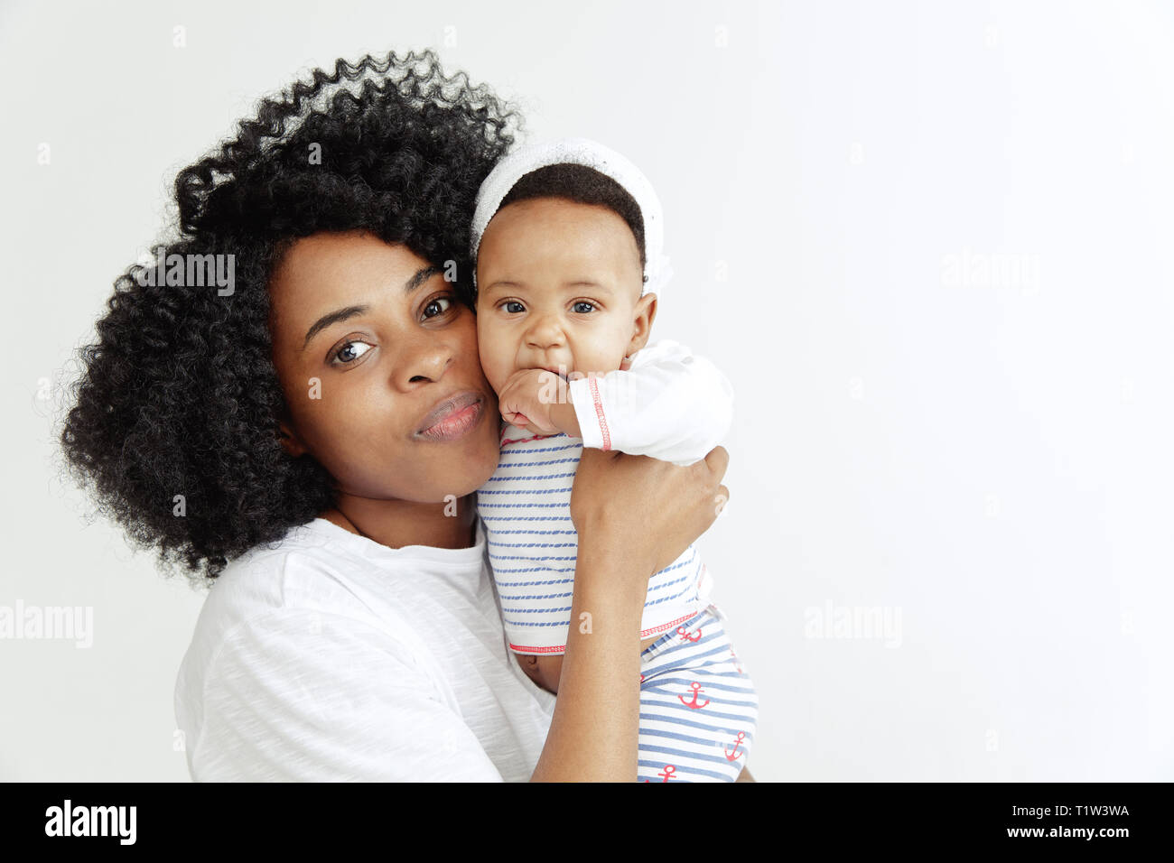 Closeup ritratto di bella donna africana tenendo in mano la sua piccola figlia su sfondo bianco. La famiglia, l'amore, lifestyle, maternità e teneri istanti concetti. La festa della mamma di un concetto o di sfondo Foto Stock