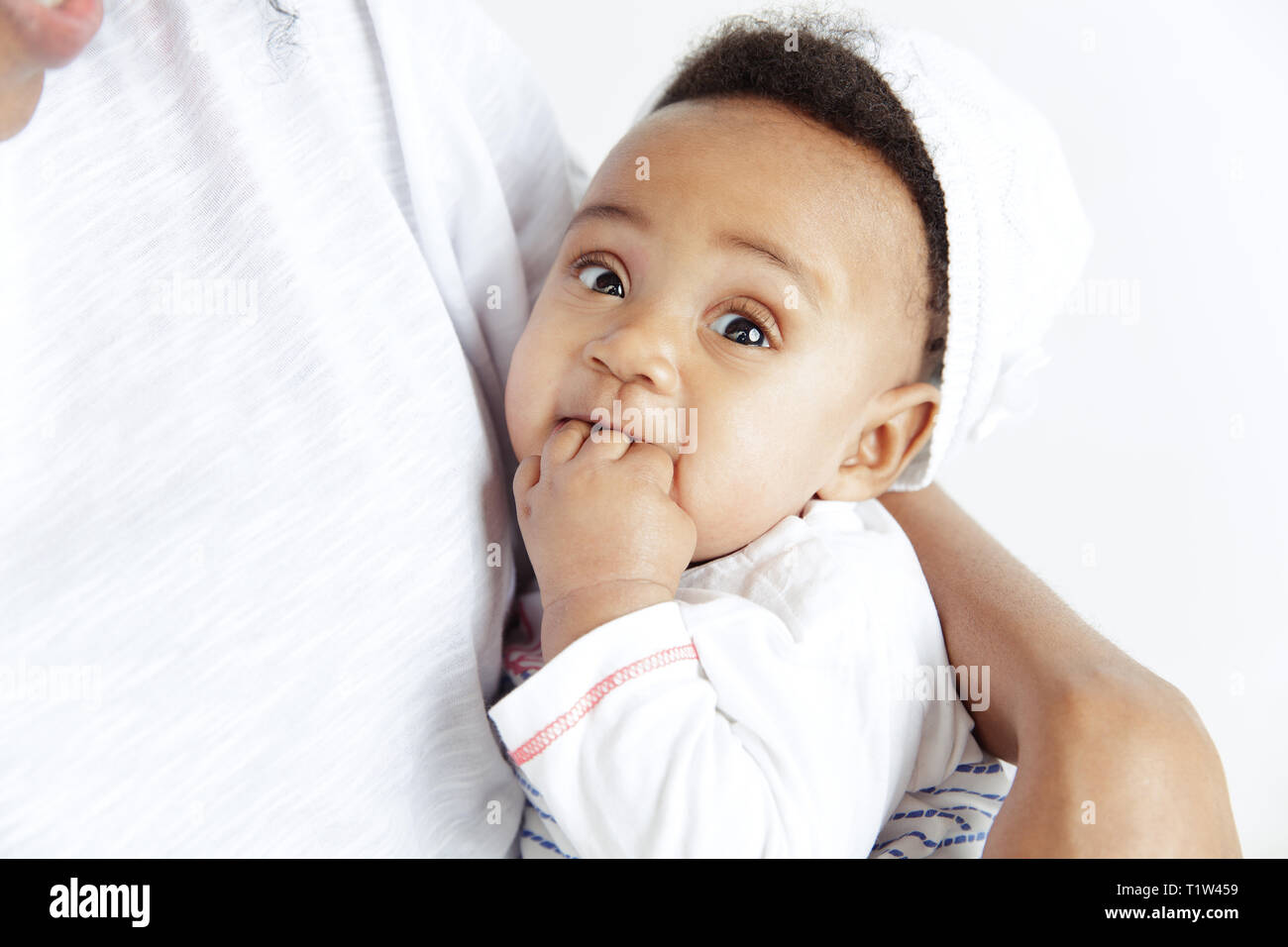 Closeup ritratto di bella donna africana tenendo in mano la sua piccola figlia su sfondo bianco. La famiglia, l'amore, lifestyle, maternità e teneri istanti concetti. La festa della mamma di un concetto o di sfondo Foto Stock