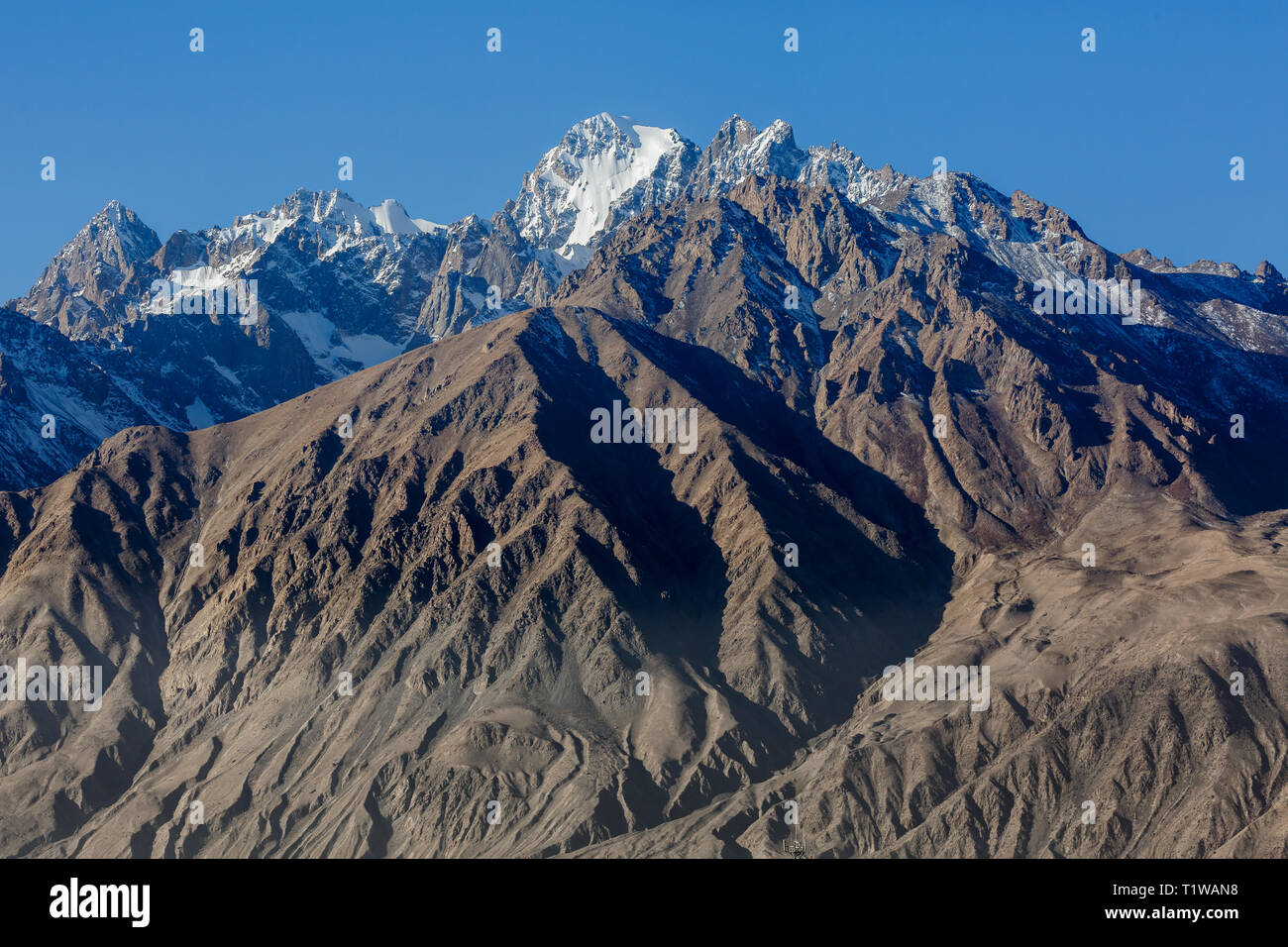 In prossimità delle montagne innevate vicino Tashgurkan. La città di Tashgurkan è meglio conosciuto per la pietra antica fortezza. Lungo la Karakoram Highway. Foto Stock