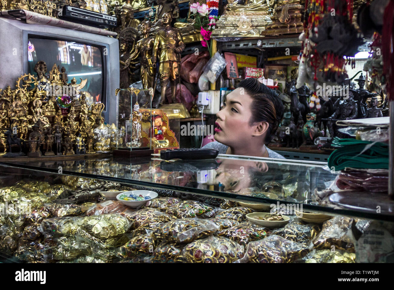 Un uomo guarda lo schermo del monitor nel negozio di souvenir del Budda tempio a Bangkok, in Thailandia Foto Stock