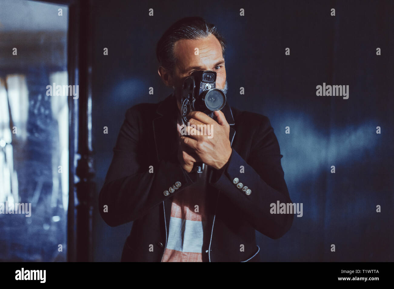 Un uomo barbuto Moviemaker con una fotocamera vintage nelle sue mani. Foto Stock