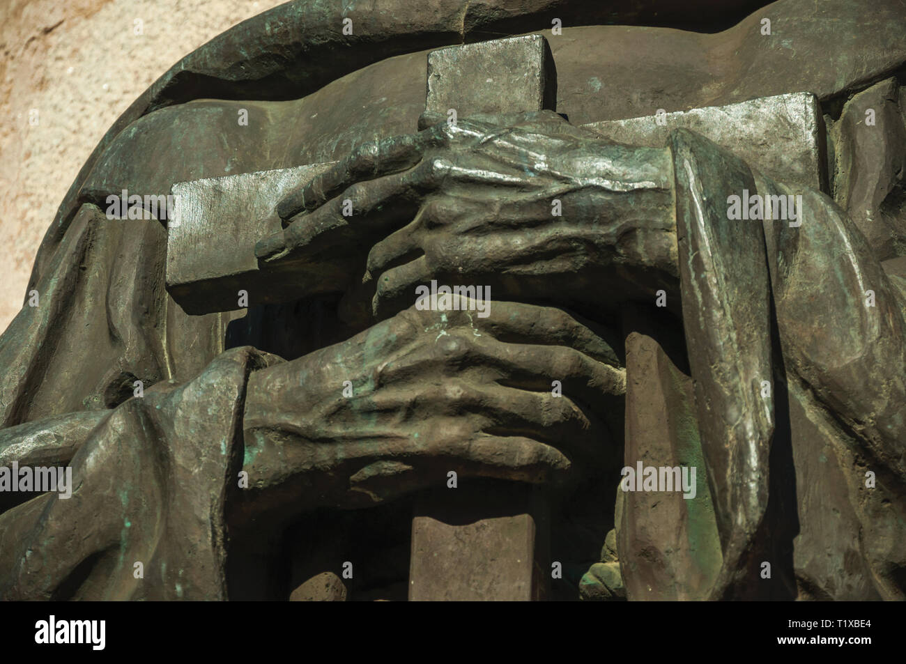 Statua in bronzo particolare del sacerdote tenendo le mani una croce su una cattedrale a Caceres. Una città affascinante con una completamente preservato centro storico in Spagna. Foto Stock