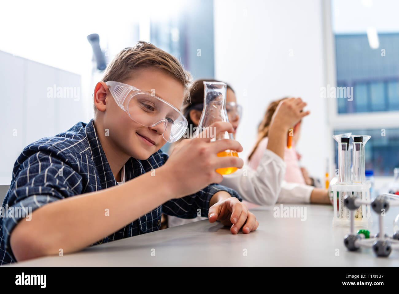 Gli alunni di occhiali di protezione bicchieri di contenimento durante la lezione di Chimica Foto Stock
