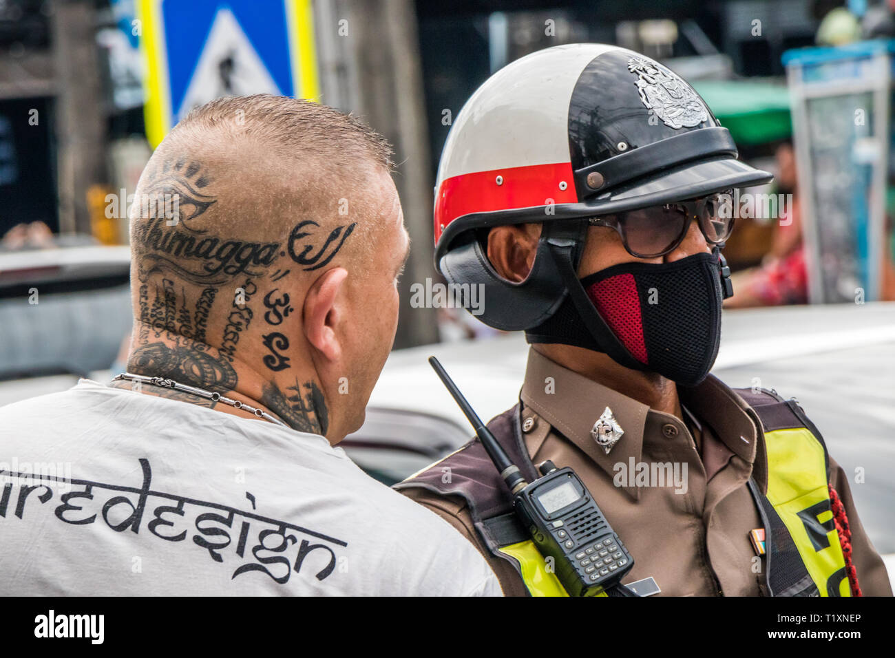 Phuket, Thailandia 17 Gennaio 2019: l'Uomo con testa tatuata a parlare con il poliziotto a Patong Beach. La polizia spesso fini turisti per reati di traffico. Foto Stock