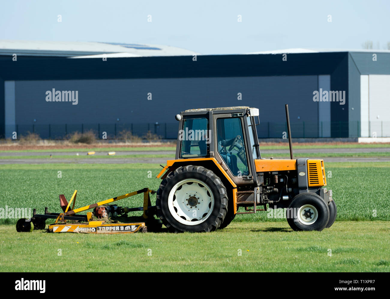 Un trattore la falciatura di erba a Wellesbourne Airfield, Warwickshire, Regno Unito Foto Stock