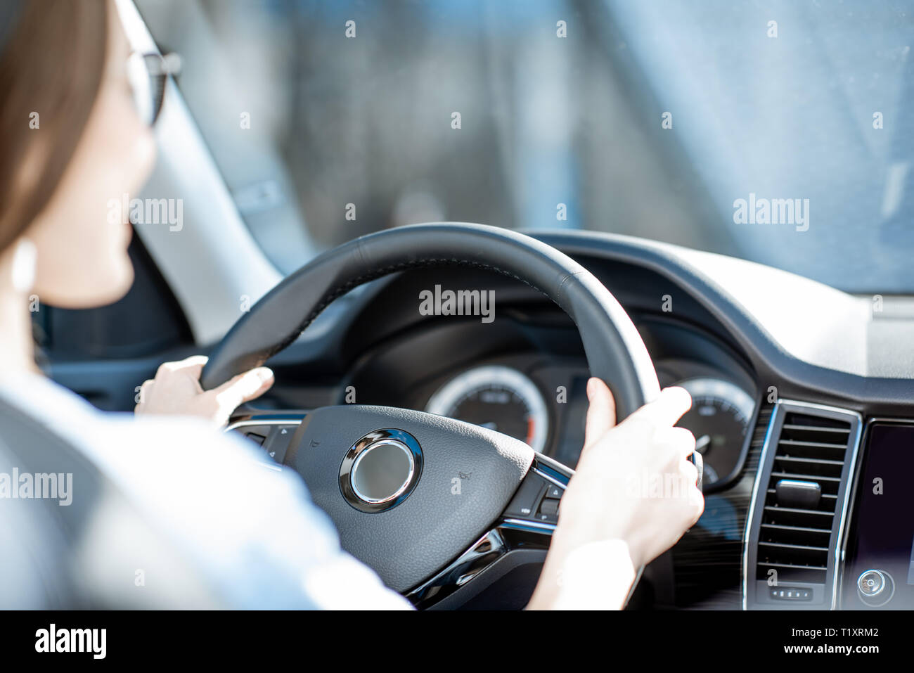 Donna che mantiene il volante durante la guida di una vettura, vista da vicino Foto Stock