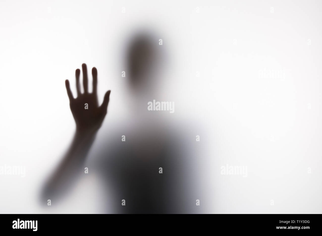 Sfocata silhouette della persona che entra in contatto con il vetro lato Foto Stock