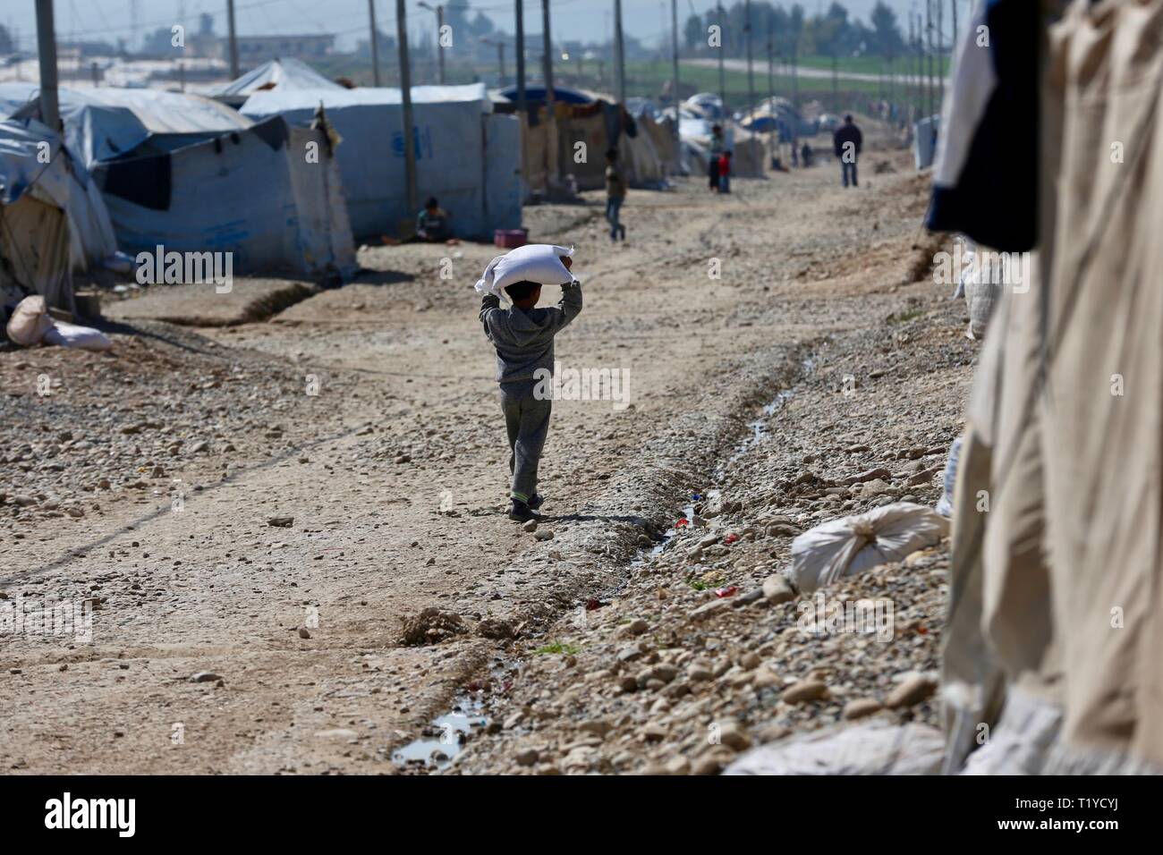 (190329) -- di Mosul, Marzo 29, 2019 (Xinhua) -- Un ragazzo porta sollievo il cibo in al-Salamiyah 1 camp, una trentina di km a sudest dell'Iraq settentrionale della città di Mosul, Iraq, 6 marzo 2019. Dopo più di un anno dopo la vittoria militare contro gli estremisti islamici membro (SI) militanti, centinaia di migliaia di iracheni sfollati interni sono ancora bloccati nei campi di concentramento, rivolta verso la scarsità di cibo mentre prive di opportunità di lavoro e servizi di base a tornare a casa. (Xinhua/Khalil Dawood) PER ANDARE CON FUNZIONE: rifugiati iracheni bloccati nei campi di concentramento, mancanza di opportunità per tornare Foto Stock