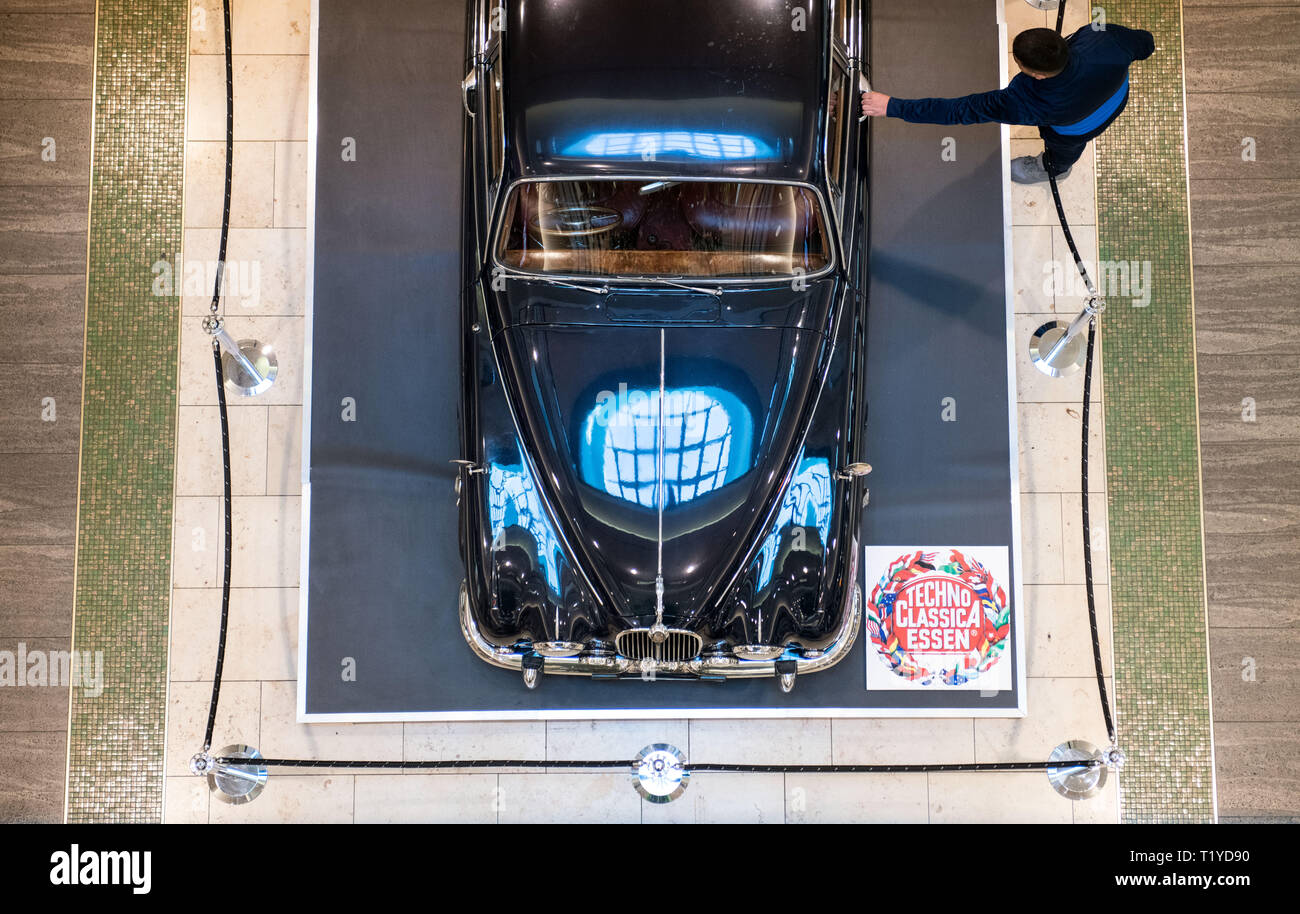 Essen, Germania. 29 Mar, 2019. Un passante prende il suo posto nella piazza Limbecker shopping center a un esposto Peugeot 302 dal 1936. Per l'annuncio della fiera TechnoClassica da 10-14 aprile, alcuni veicoli del classico auto equo può essere già ammirato in anticipo per un paio di giorni nel centro commerciale. Credito: Bernd Thissen/dpa/Alamy Live News Foto Stock