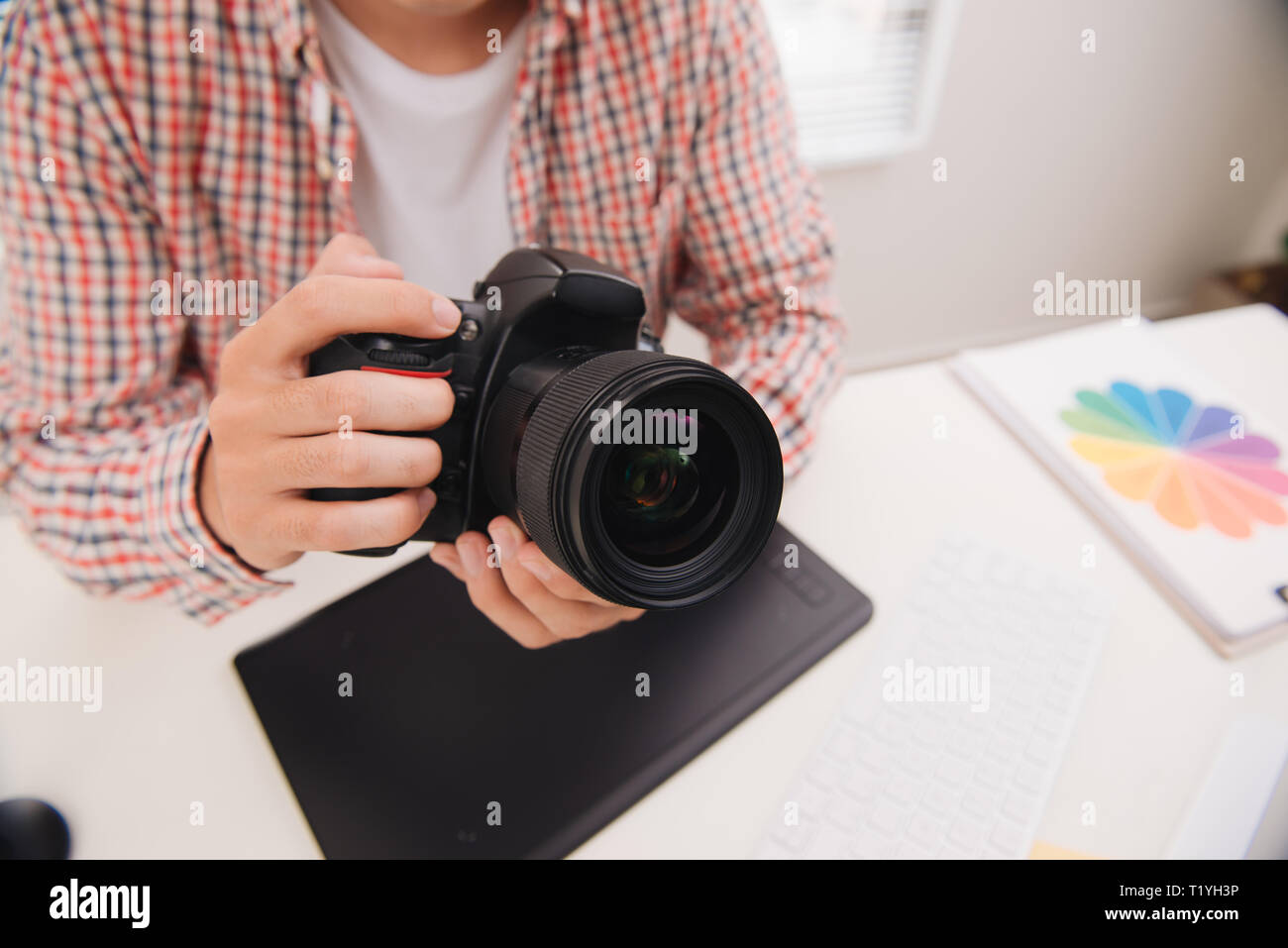 Fotografo maschio, seduto alla sua scrivania, guardando alla fotocamera Foto Stock