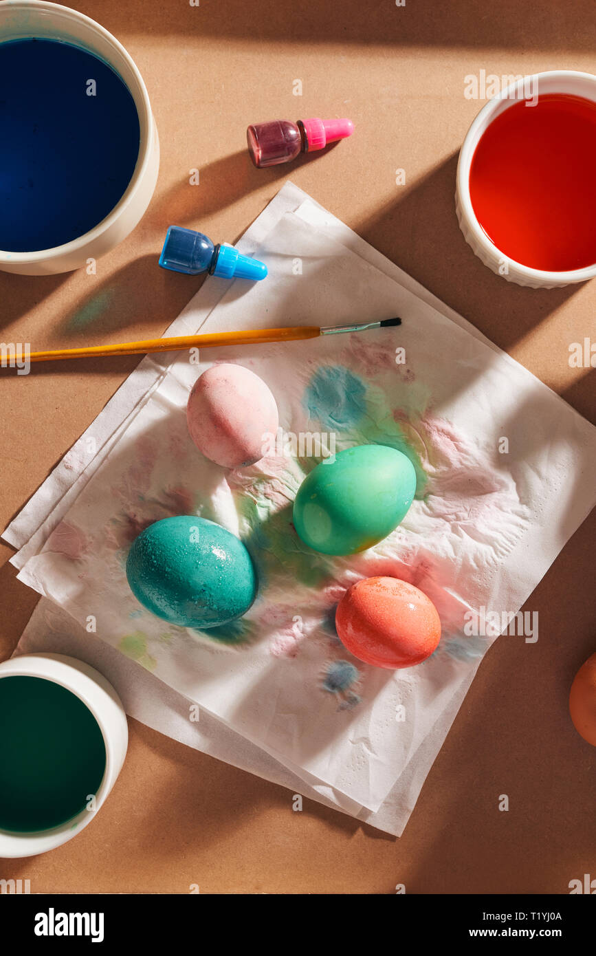 Uova, vernici colorate, spazzole, matite su uno sfondo di legno, la colorazione delle uova, la preparazione alla Pasqua, la molla Vacanze stagionali Foto Stock