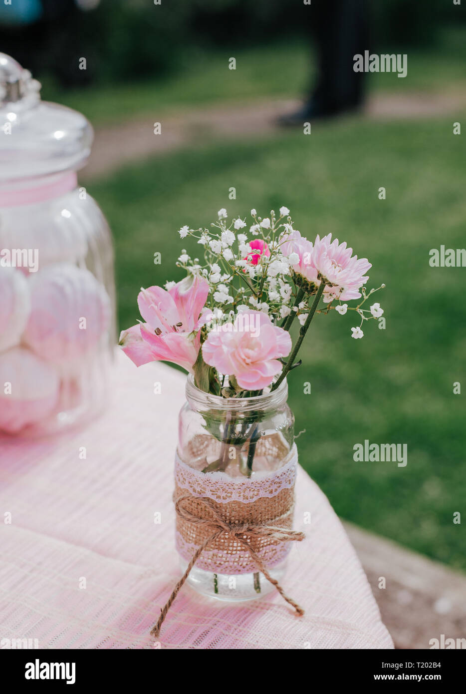 Fiori di colore rosa in vetro decorato in rosa tabella, dolci, su sfondo verde. Concetto della donna o della mamma Foto Stock