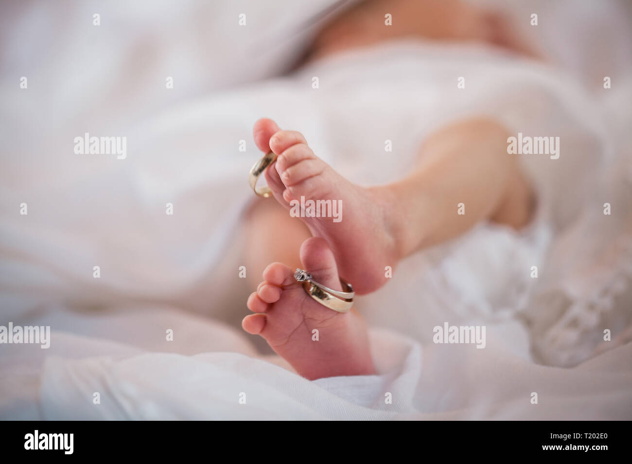 Close up piedi del bambino con gli anelli di nozze su grandi dita. Foto Stock