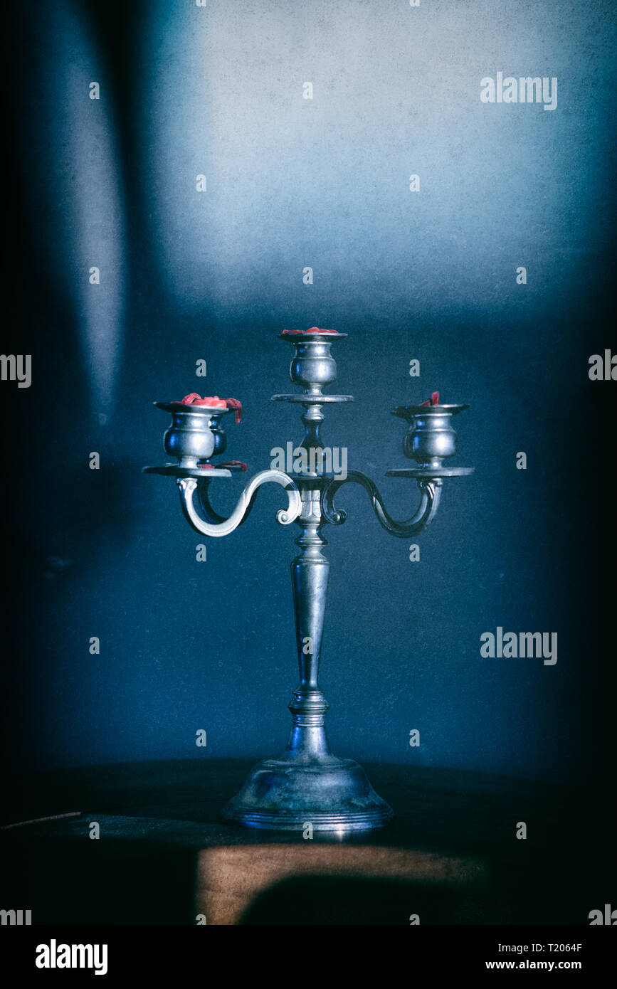 Moody moonlight immagine di ornati candelabri getta un' ombra sulla parete dietro. Le candele rosse vengono bruciate. Misteriosa immagine granulosa. Foto Stock
