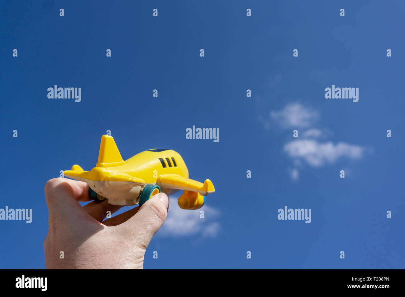 Giallo piano giocattolo in volo per il bel cielo azzurro, lo spazio negativo, concetto di andare a fare una vacanza magica, una destinazione da sogno Foto Stock