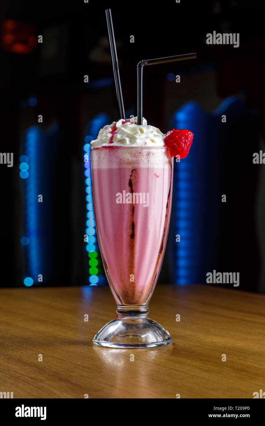 Frullato di fragole con panna montata su di un tavolo di legno Foto Stock