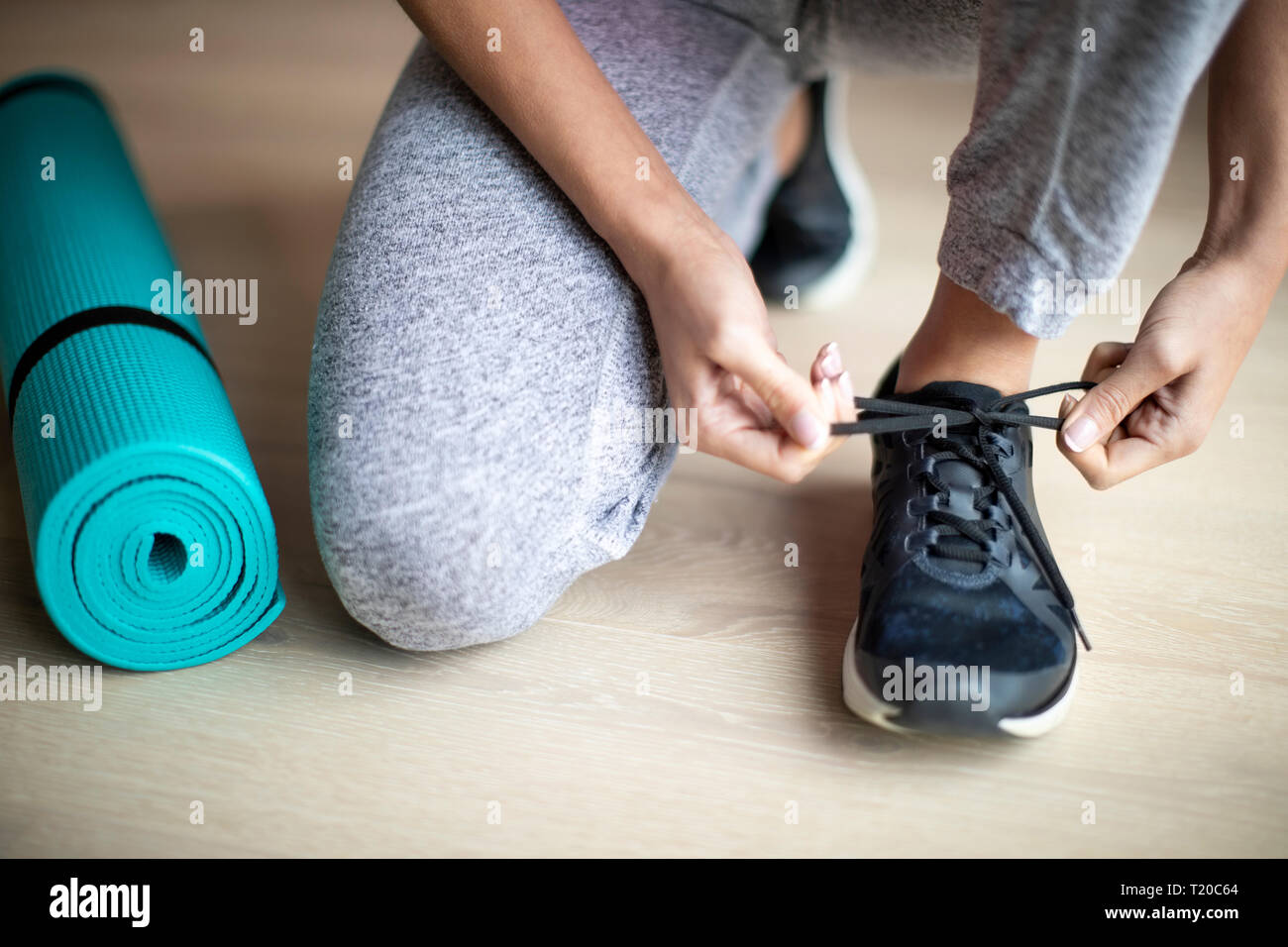 Close up della donna la legatura dei lacci delle scarpe da ginnastica prima di esercitare a casa Foto Stock