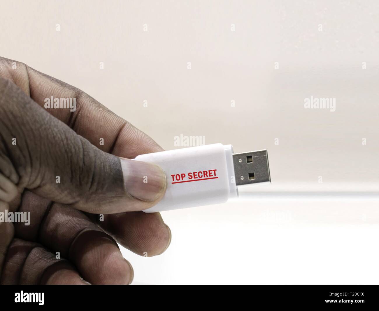 Per informazioni classificate. Persona africana la mano che regge un drive flash USB con un Top Secret etichetta, contenenti informazioni riservate. Foto Stock
