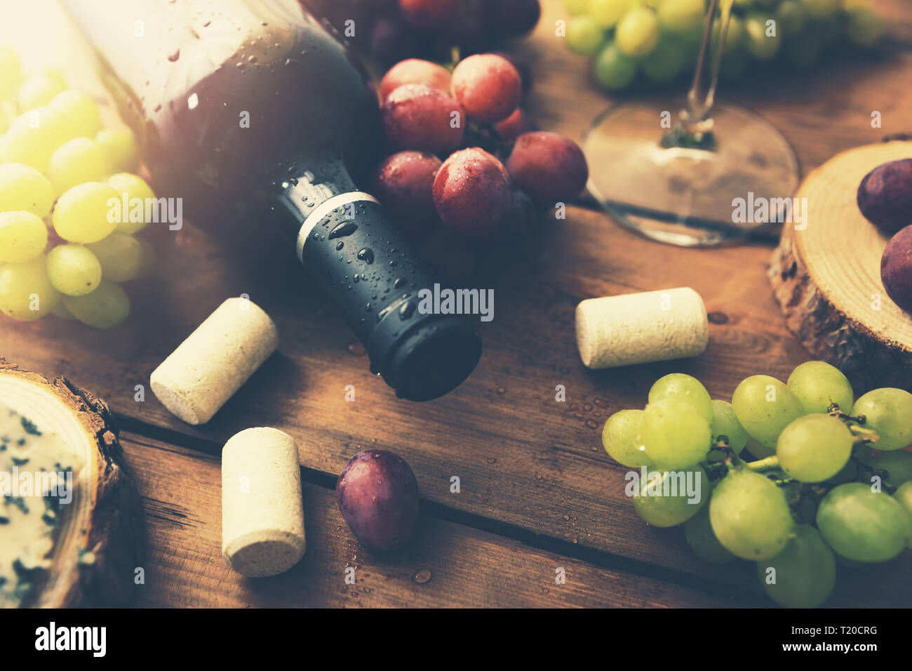 Rosso bottiglia di vino con uve sul vecchio sfondo di legno Foto Stock