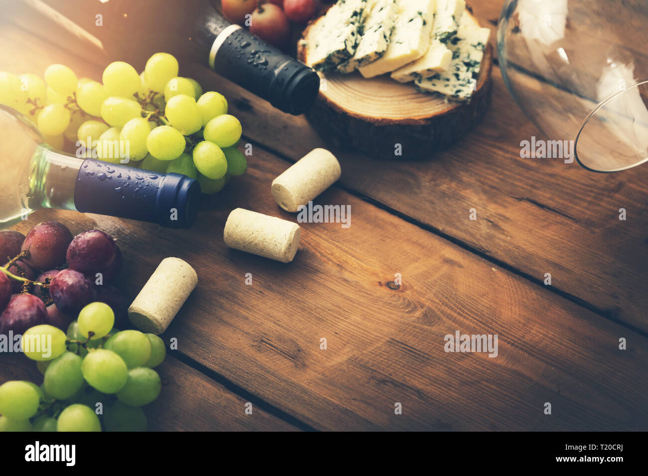 Le bottiglie di vino con uve e formaggio su sfondo di legno. spazio copia Foto Stock