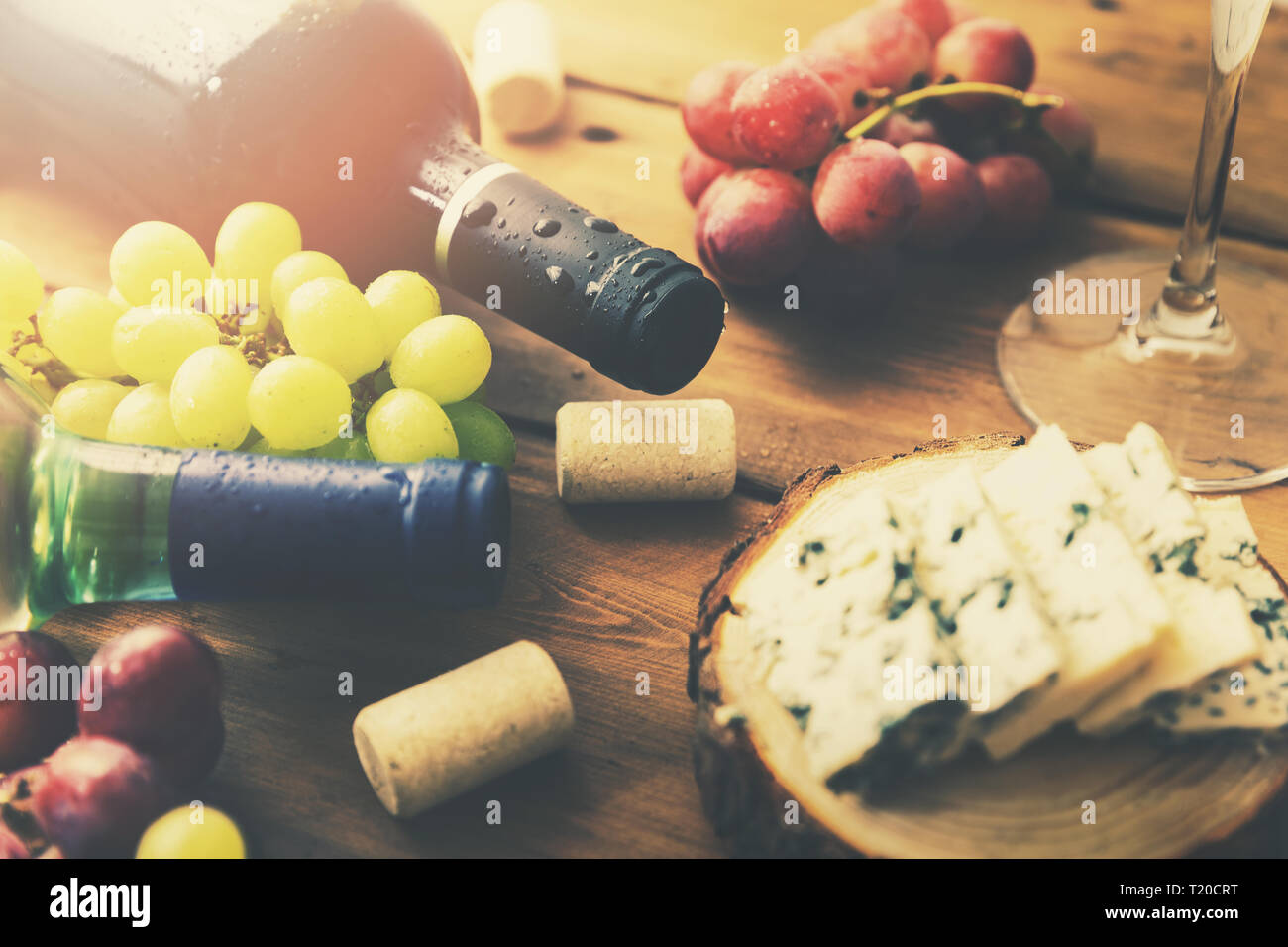 Le bottiglie di vino di uve e formaggio sul vecchio tavolo in legno Foto Stock