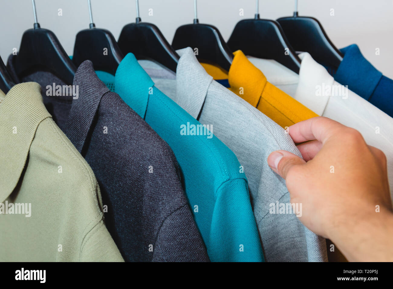 Maschio lato afferrando un cotone polo t-shirt da appendiabiti Foto Stock