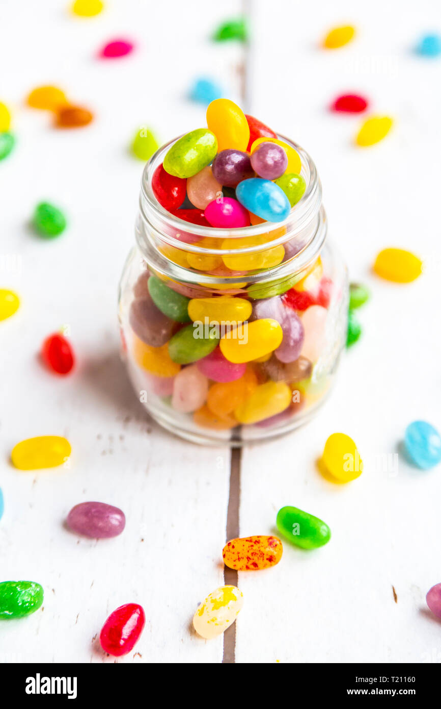 Di vetro colorato jellybeans dolce su legno bianco Foto Stock