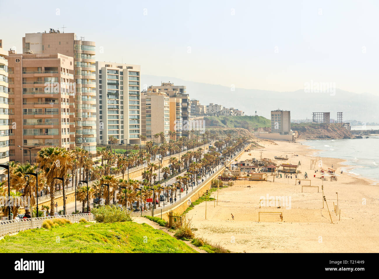 Passeggiata sul lungomare con un moderno edificio, una strada, spiaggia di sabbia e il mare, Beirut, Libano Foto Stock