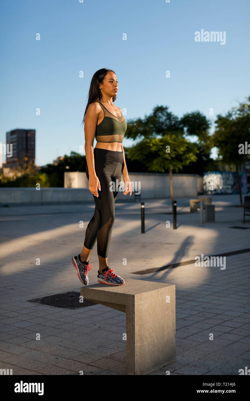 Sporty giovane donna in piedi sul blocco di calcestruzzo nella città Foto Stock