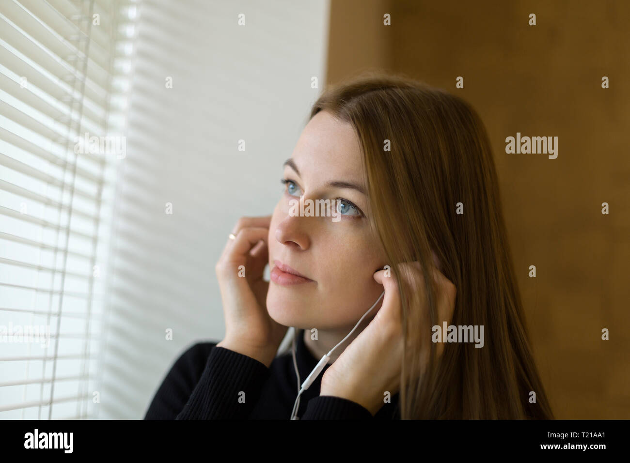 Ritratto di donna finestra vicino a mettere su auricolari Foto Stock