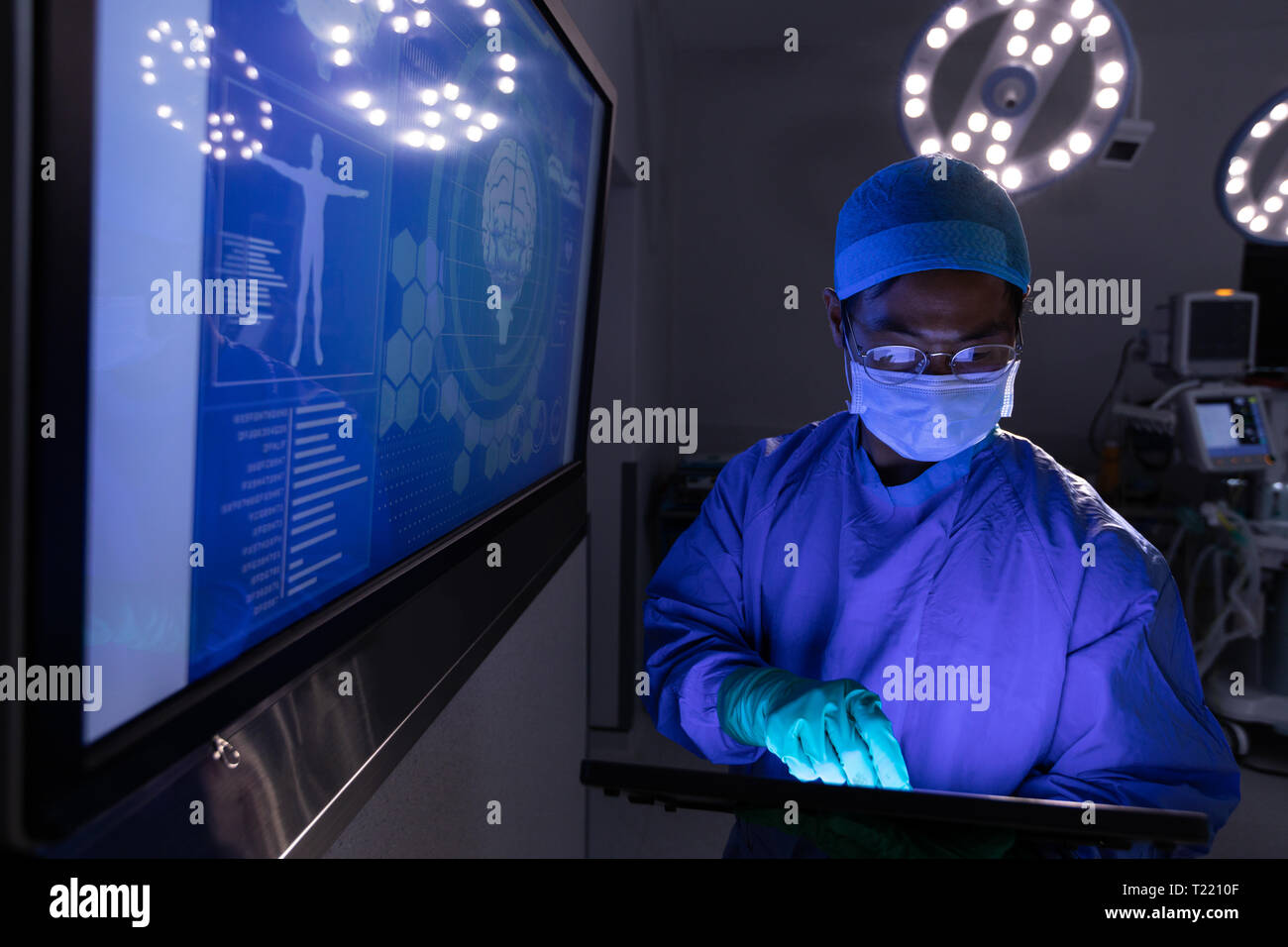 Chirurgo maschio utilizzando tavoletta digitale in sala operatoria in ospedale Foto Stock