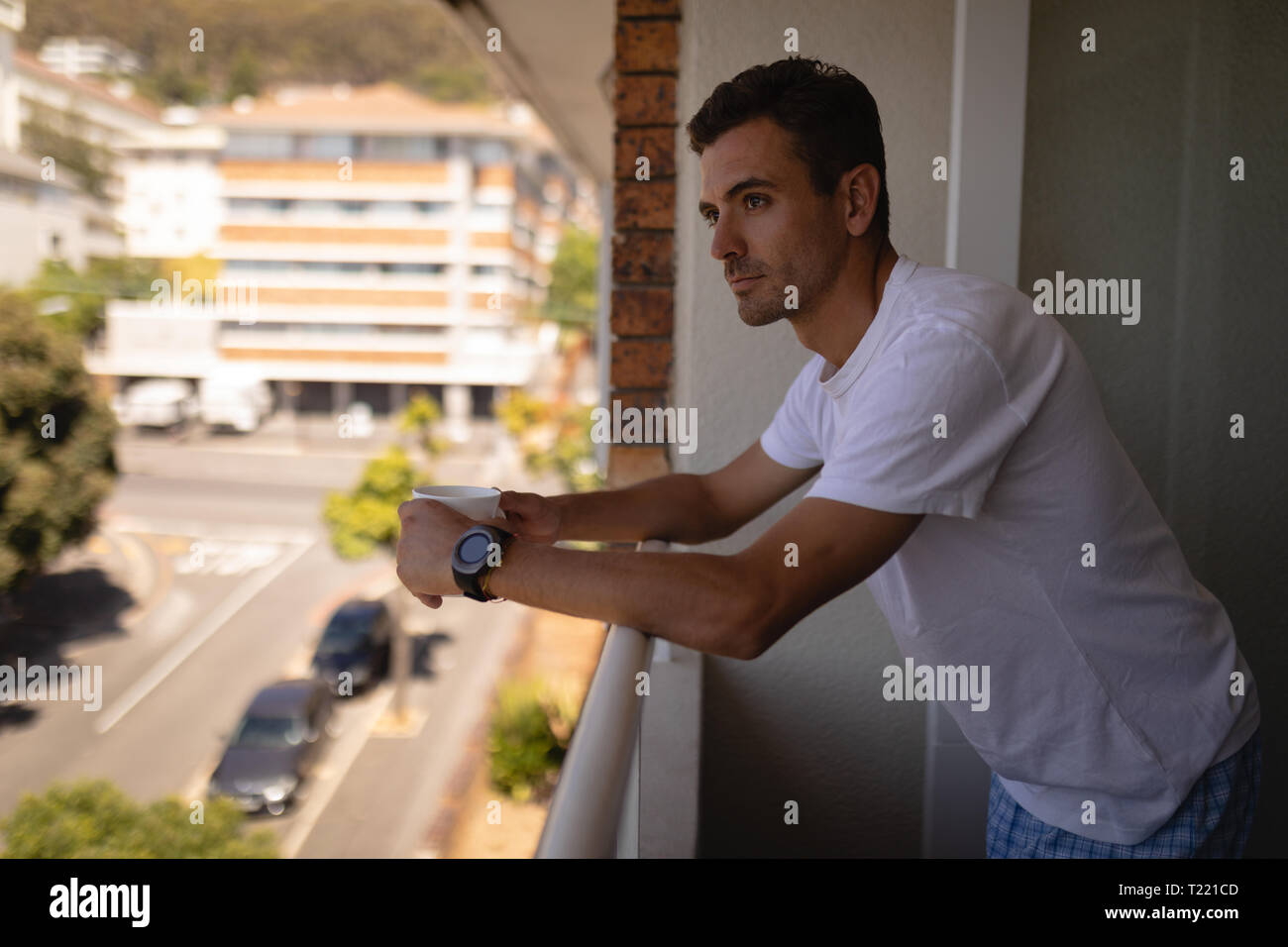 L'uomo con la tazza di caffè in piedi in balcone a casa Foto Stock
