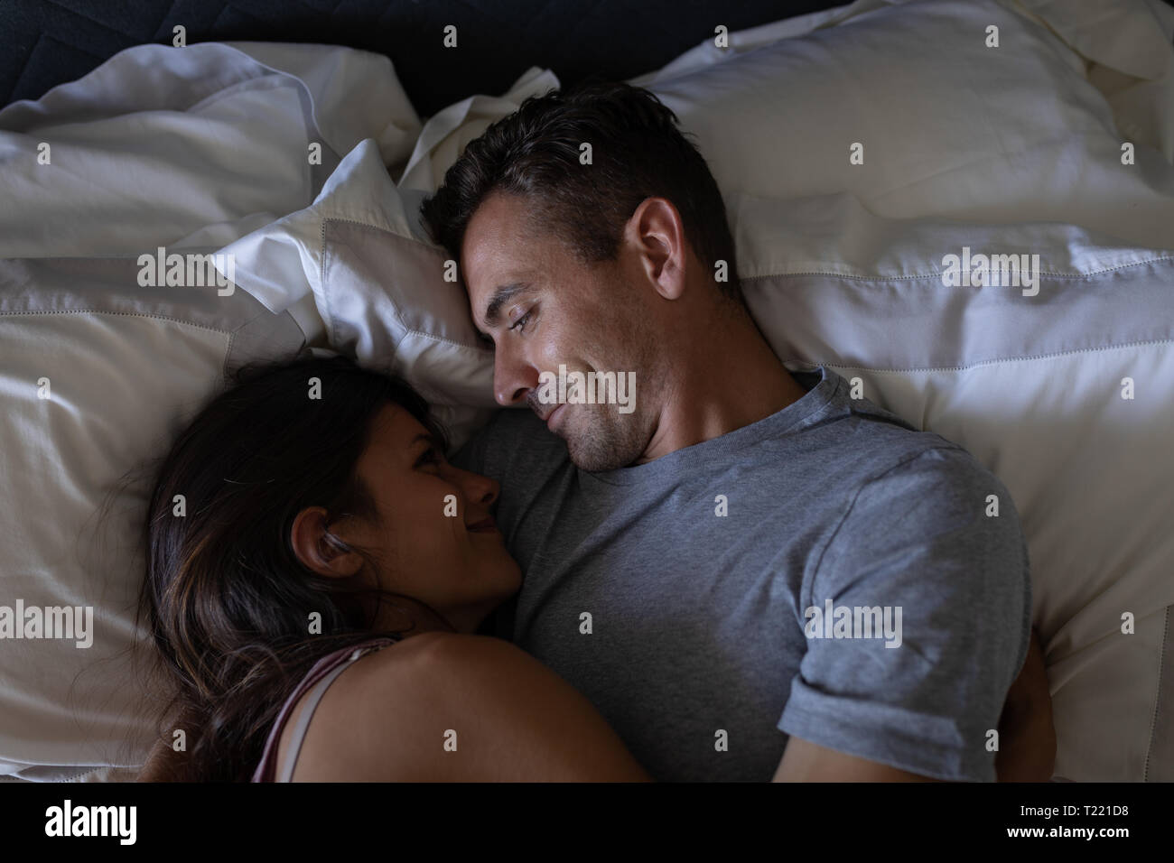 Coppia romantica guardando ogni altro mentre giaceva a letto a casa Foto Stock